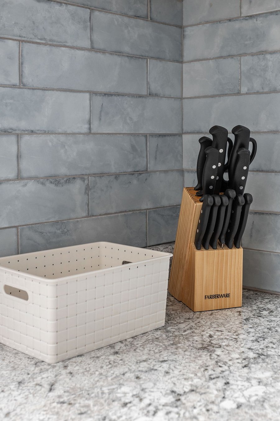 Sleek and organized kitchen setup featuring a Farber ware knife block against a stylish tiled backsplash.