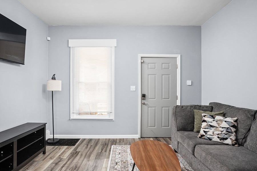 Cozy living room with a gray couch, decorative pillows, a wooden coffee table, and a TV mounted on the wall.
