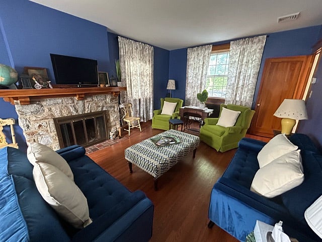 Shared spaces include half-bath on first floor, kitchen, dining room, living room, and outside seating area.
Dining room consists of large wooden table, six upholstered chairs with additional seating around, a rocking chair, charming wall art, and an curio cabinet complete with games and karaoke.