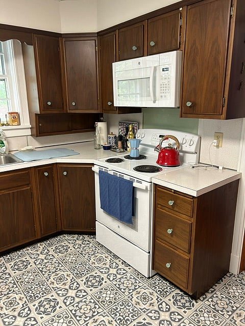 The spacious kitchen has kept some of it's old charm with the rich oak cabinets, however, the kitchen is fully stocked with modern amenities, a new kitchen island, stunning Spanish tile-like vinyl, iron and ironing board, vacuum cleaning, cleaning supplies, towels and more.