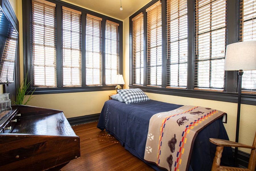 Sitting room off of primary bedroom, usually with loveseat, but shown with a twin daybed. Wall-mounted TV.