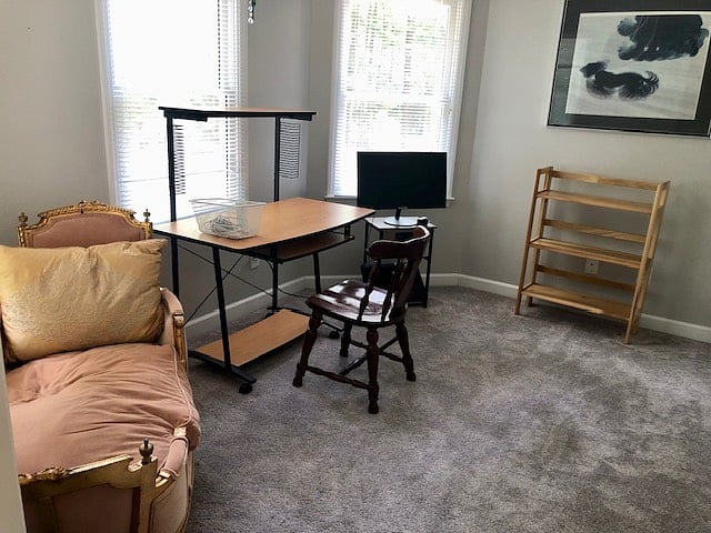 Study or office adjacent to master bedroom with desk, chaise lounge, bookshelf and monitor.