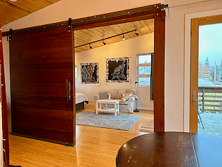View from dining area showing large barn door entry to bedroom.