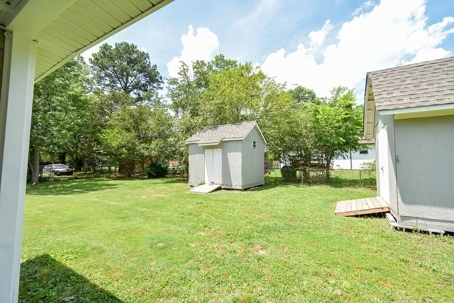 View of fully fenced in back yard - one shed can be used for tenant storage