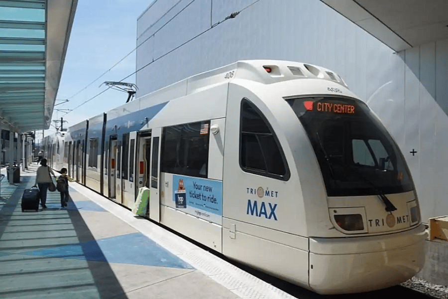 The light rail MAX is located at the west end of the Airport Terminal. Follow the signs after exiting security or getting your bags. Then pay $2.80, board and relax until you reach the NE 7th Ave station.