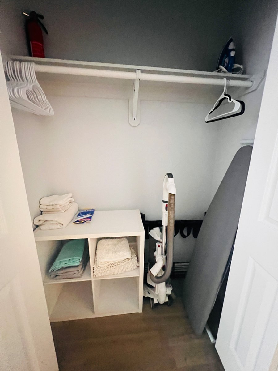 Closet with ironing board, iron, hangers, rags, fire extinguisher 