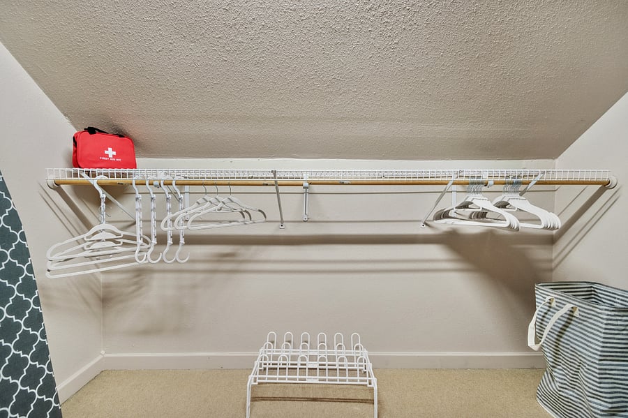 Large walk in closet with alot of hangers, iron and board, clothes steamer and other cleaning items