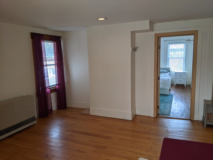 View of primary bedroom from living room; window to the front of the unit/house.