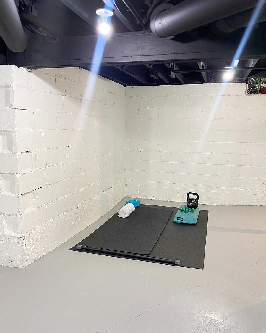 The yoga workout area next to the laundry station is equipped with small weights, a mat, a mirror, and a step, making it ideal for unwinding at the end of the day or starting your morning with a workout while your laundry dries.