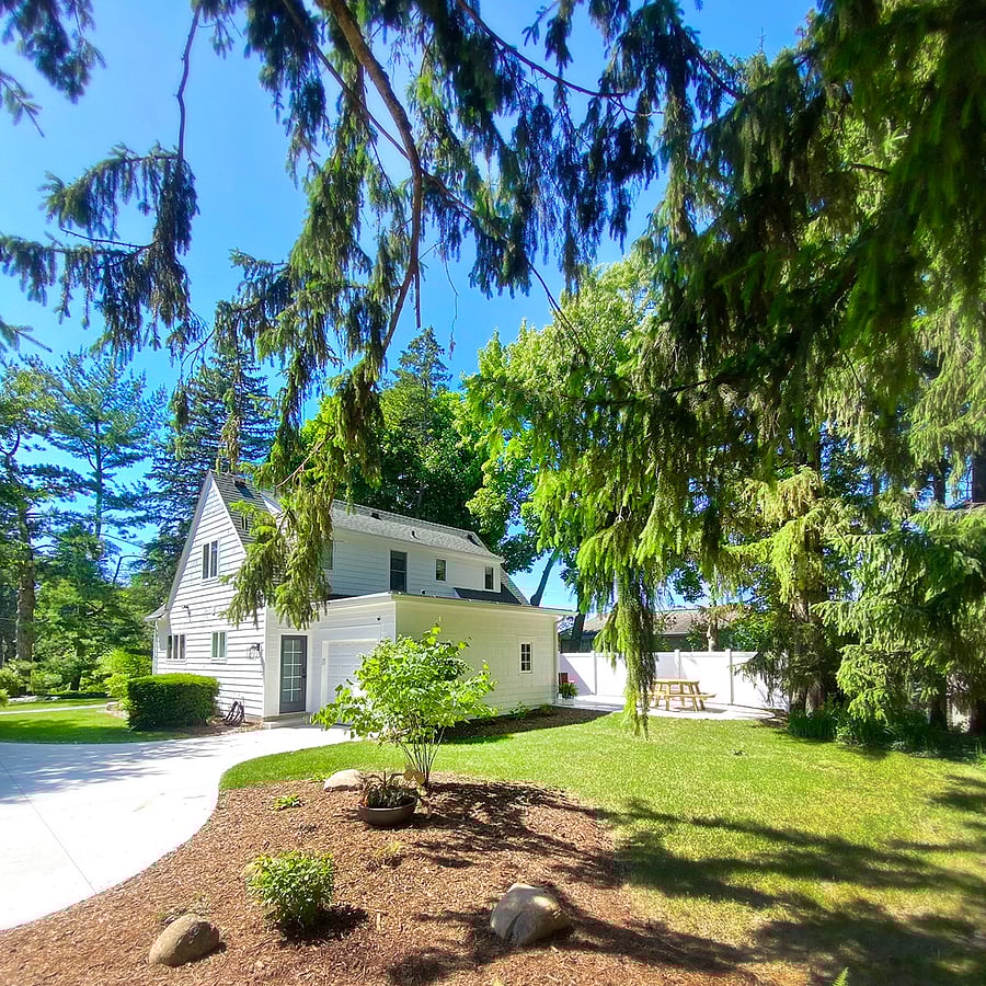 The back view of property features a tranquil yard, with the driveway elevated from the road and capable of accommodating multiple cars. For added safety, exterior lights and a motion sensor is installed, along with security cameras at entry points.