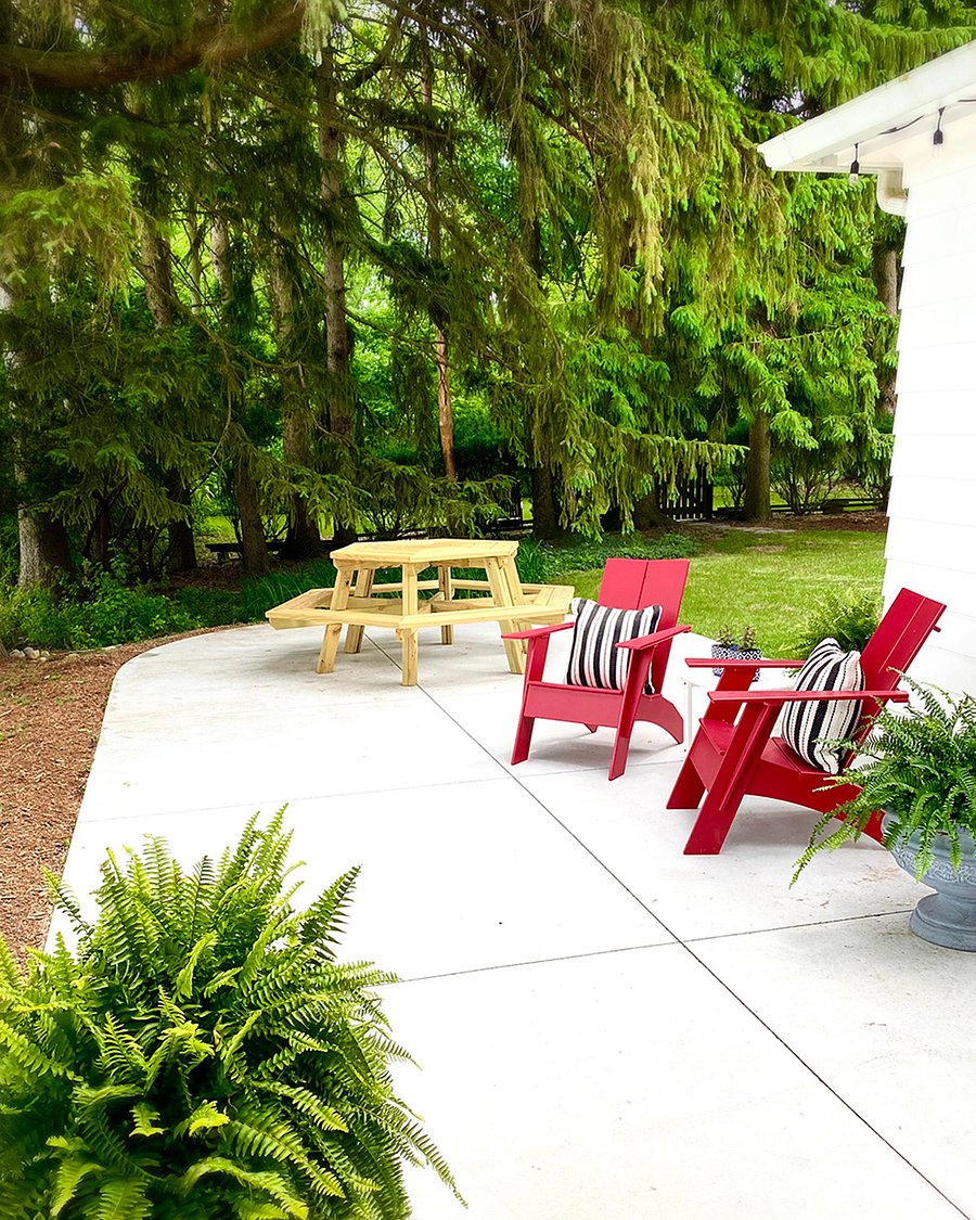 Enjoy your morning coffee in the comfortable Adirondack chairs or gather around the picnic table for outdoor dinners. A cozy bench sits beneath the overhang, illuminated by string lights, creating a warm ambiance for evenings outdoors.