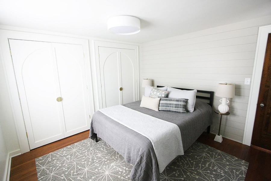 The second floor bedroom features a queen bed and soft bedding, a floor length mirror, large closet with hangers, and a luggage rack. Steps away is a full bathroom with tiled walk in shower.