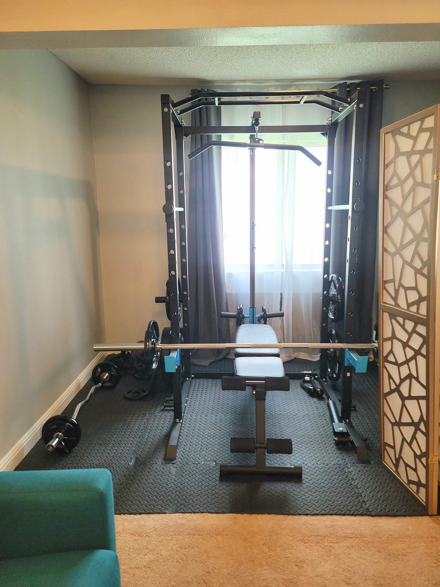 Weight room with squat rack, and adjustable dumbbells located in living room den