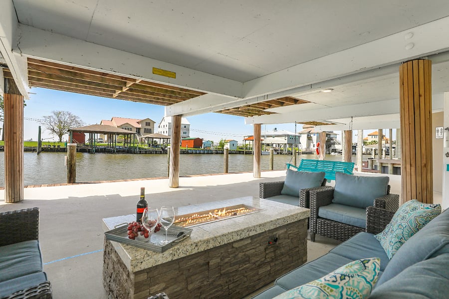 Another view of the fire pit coffee table surrounded by a full sized couch, love seat, and two chairs with the chair swing in the background. There is also a table that seats 8 and two picnic tables.
