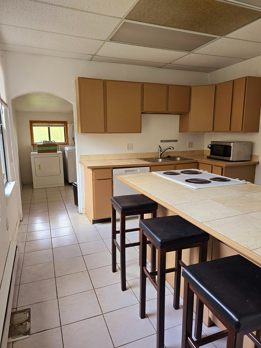 Kitchen with dishwasher, garbage disposal in sink, microwave, Keurig compatible coffee maker, island range. Laundry area in the back.