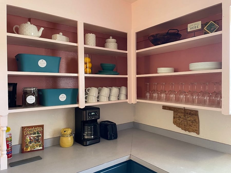 Kitchen supplies include: coffee and tea essentials (creamer, sugar packets, and sugar substitute packets), plastic plates and bowls, a salad bowl, dinner and salad plates, and a set of wine glasses.