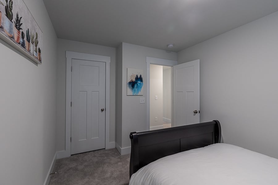 The second bedroom has a queen sized bed and a closet with hangers.