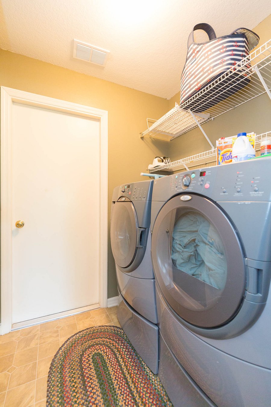 Front loading washer and dryer by Whirlpool. Positioned on risers that pull out for extra storage. Elevated drums that are back friendly.