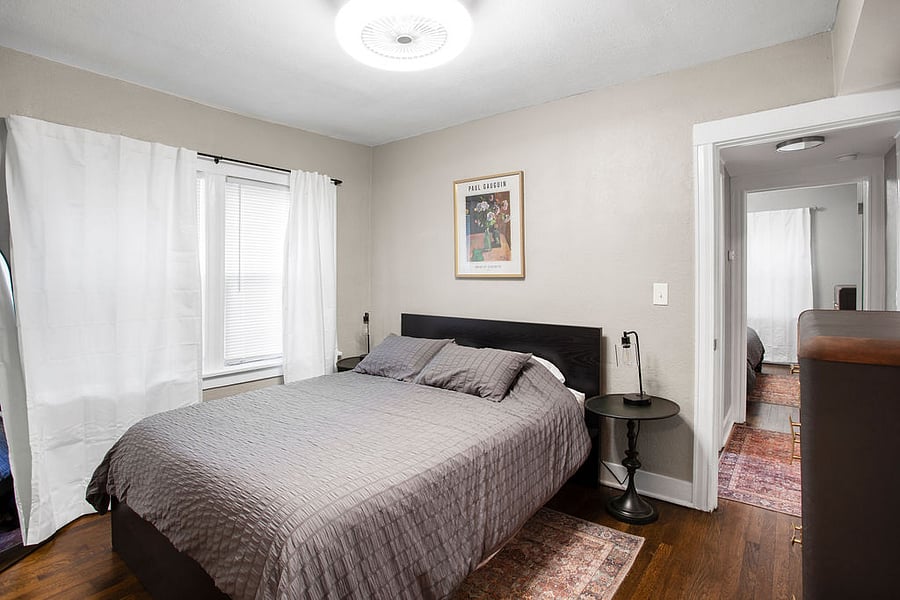 The bedroom has blinds and soft curtains. 