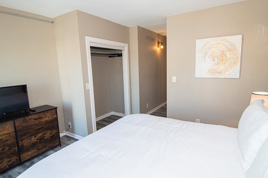 Front bedroom. Closet straight ahead. Dresser and smart TV.  En suite bathroom around the corner.
