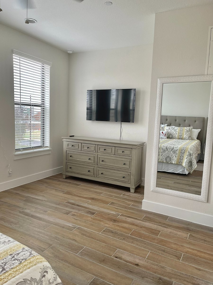 Main bedroom TV and full size dresser and wall mirror.