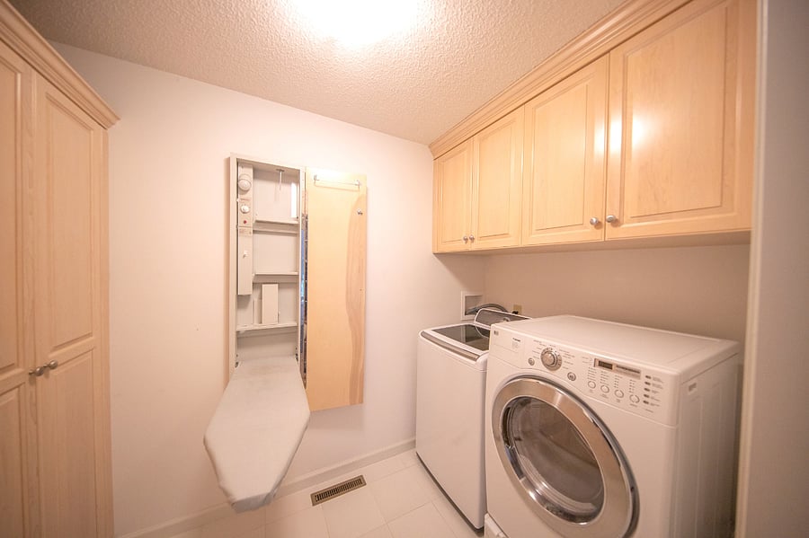 In unit laundry with ironing board and storage.