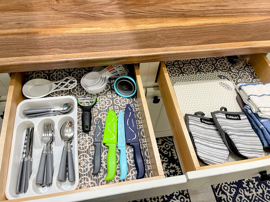 plenty of kitchen utensils, measuring cups, cheese grater, mixing bowls, pots and pans, knives, cutting boards, towels and hot pads