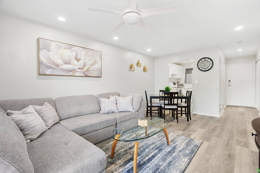 Living Room with comfortable couch and dining room table for 4. Entry to Kitchen and hallway to main entrance