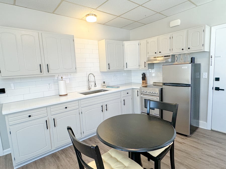 The new quartz countertops and tiled backsplash, paired with stainless steel appliances, create a cozy kitchen atmosphere.