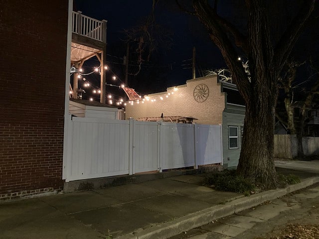 Nightime view of lighted courtyard/patio and street parking spaces.