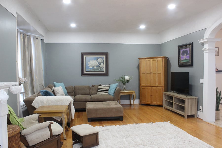 The living room features a sitting area around the TV on one side, and storage for extra blankets.