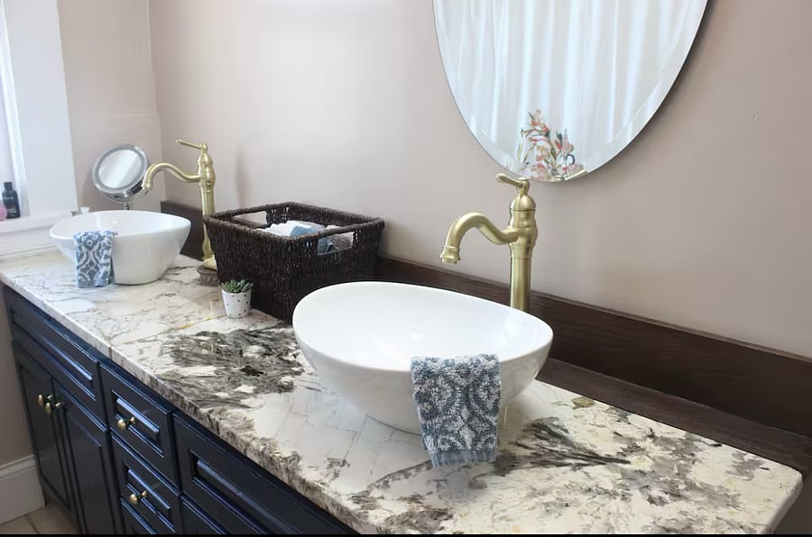 Granite countertop with plenty of storage, vessel sinks and brushed gold fixtures.