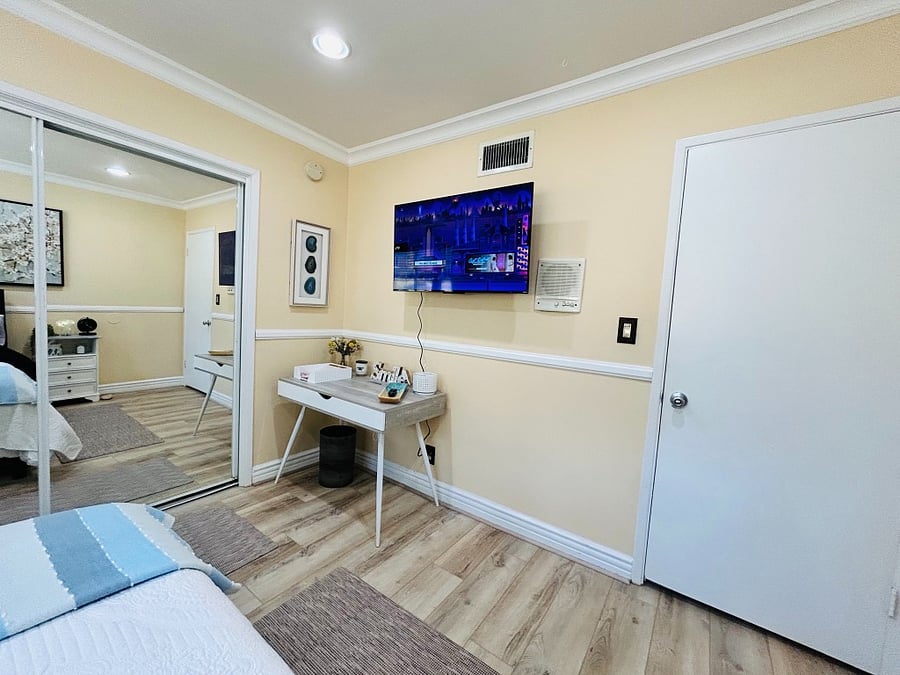 Bedroom with desk/chair and smart TV.