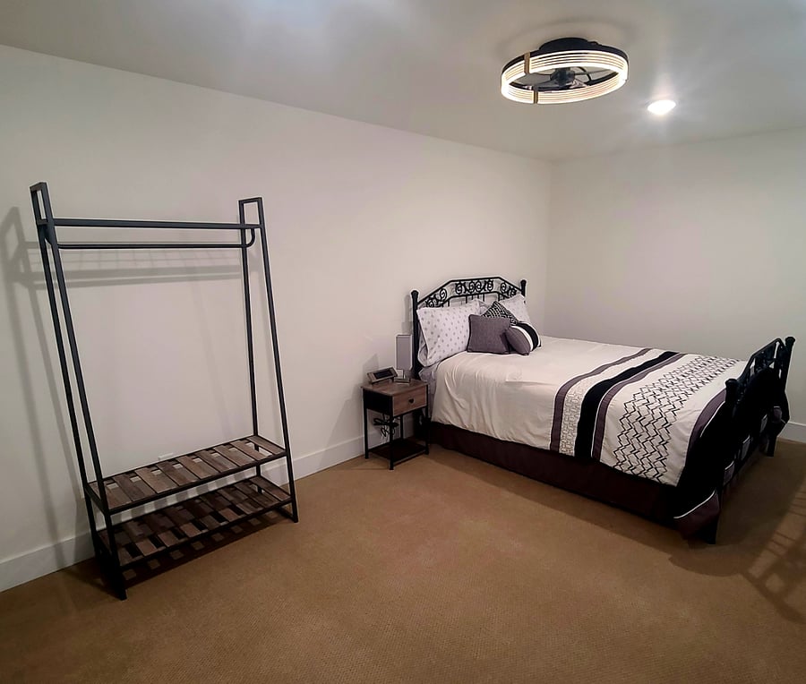 Queen bed in Loft bedroom. Clothes hanger with storage bins and tall 5 drawer dresser.