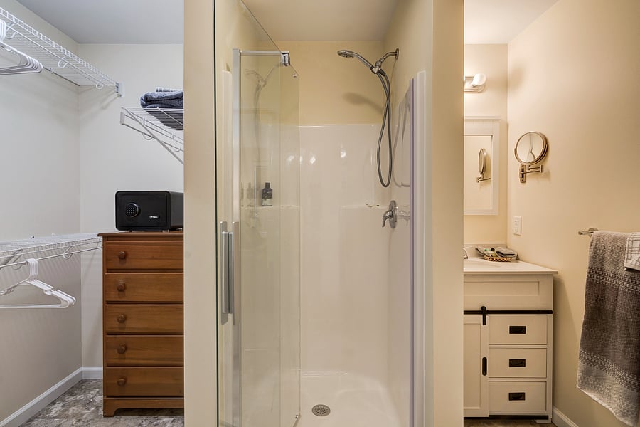 Primary bathroom includes walk in shower, vanity, toilet, bureau and hanging closet space and safe.