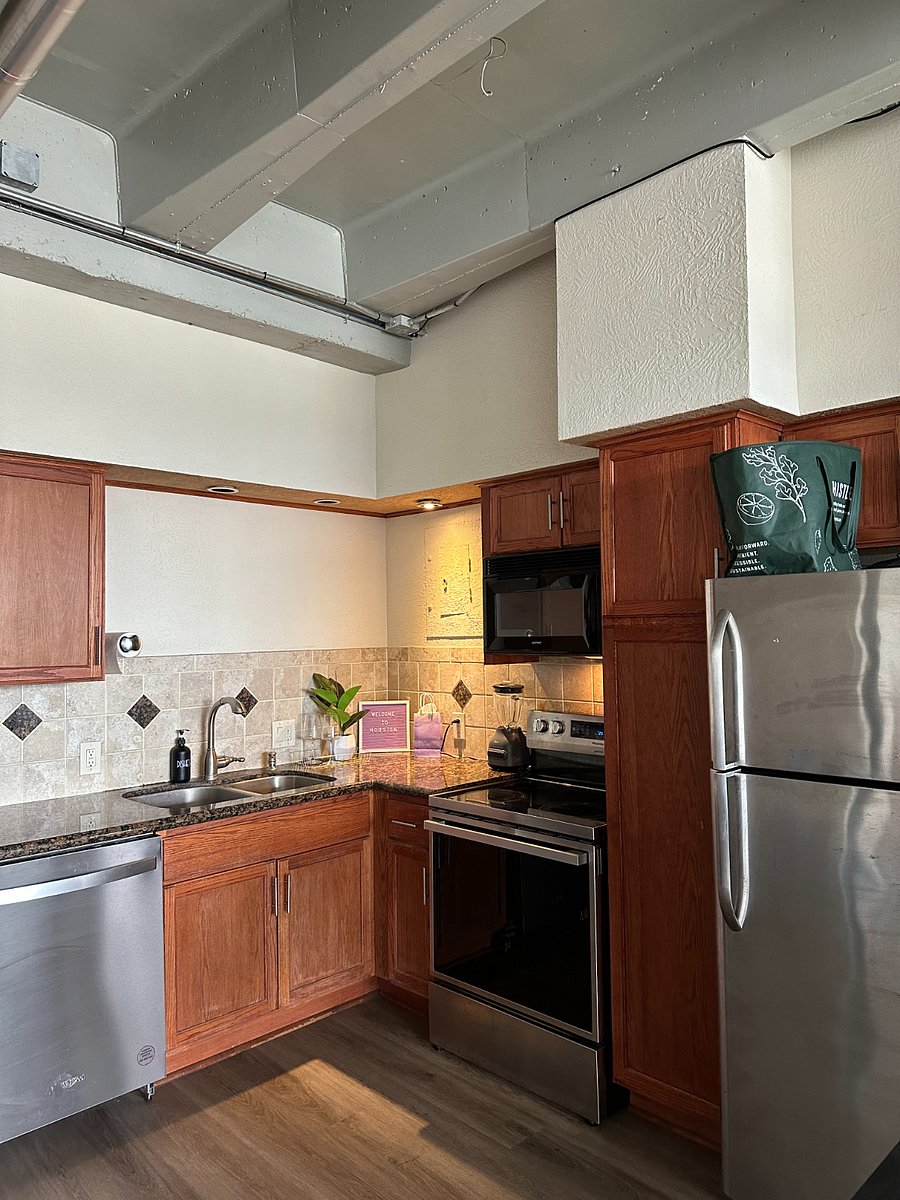 Kitchen equipped with coffee bar, blender, stove with airfryer mode, new stainless steel appliances, and insulated grocery bag for convenience. 