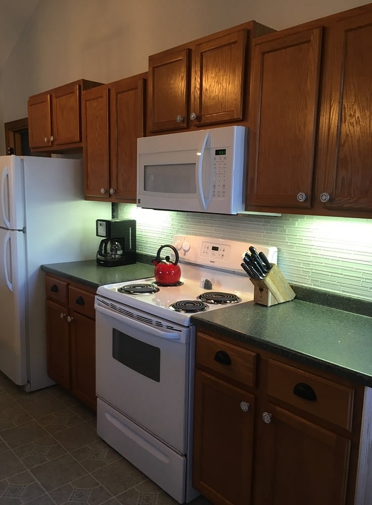 Kitchen with glass tile backsplash, knife block, plenty of cooking/baking supplies, and plenty of cabinet space.