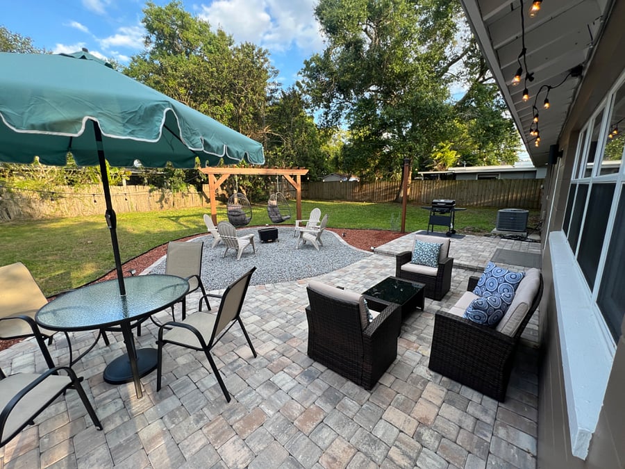 Paved patio, outdoor seating, bbq grill, and large yard space.