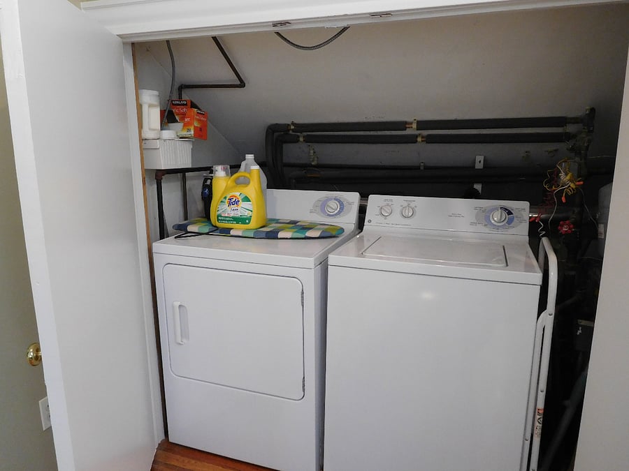Full-size laundry in unit with laundry supplies and iron.