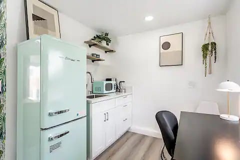Classic 50's retrofit refrig & microwave. Cute, right? Courtz coutertop and backsplash with real wood open shelves. 
Coffee maker, electrical kettle, toaster plus a portable eletrical stove hidden in the drawer makes this kitchenette very functional