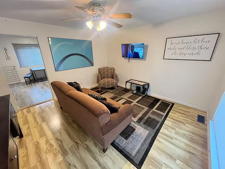 Living room seating with sofa, armchair, and wall-mounted TV.
