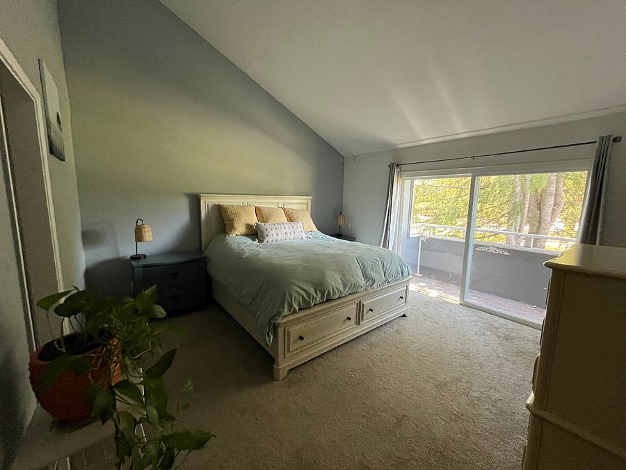 Primary bedroom with a king bed, dual nightstands, and balcony with view of golf course.