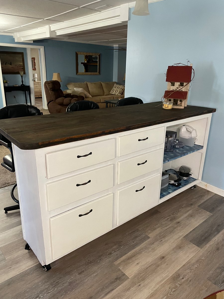Island separating kitchen from dining room has 3 leather bar chairs.