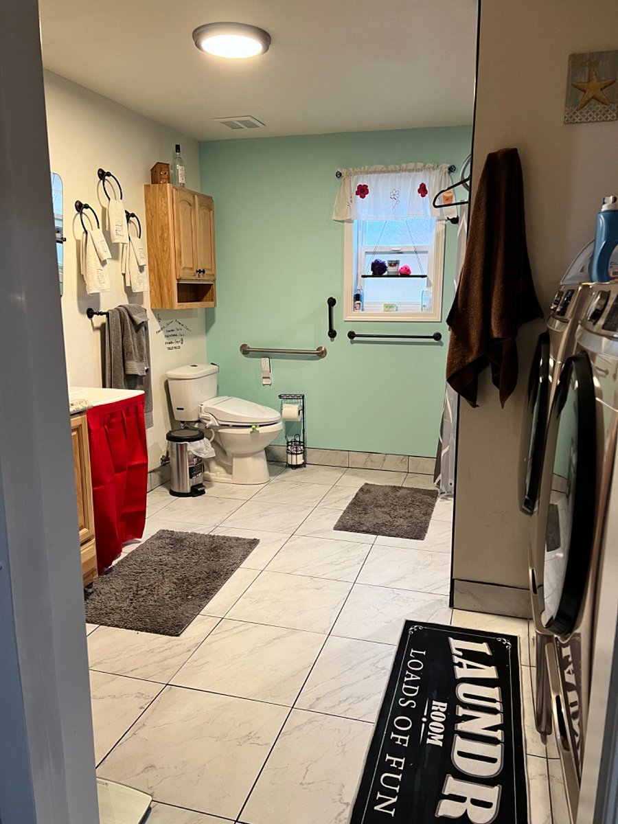 Large 11'5" x 10'8" bathroom with heated tile floors. To the right is the washer/dryer and large walk in shower. To the left is the sink, counter, and floor to ceiling storage cabinet.