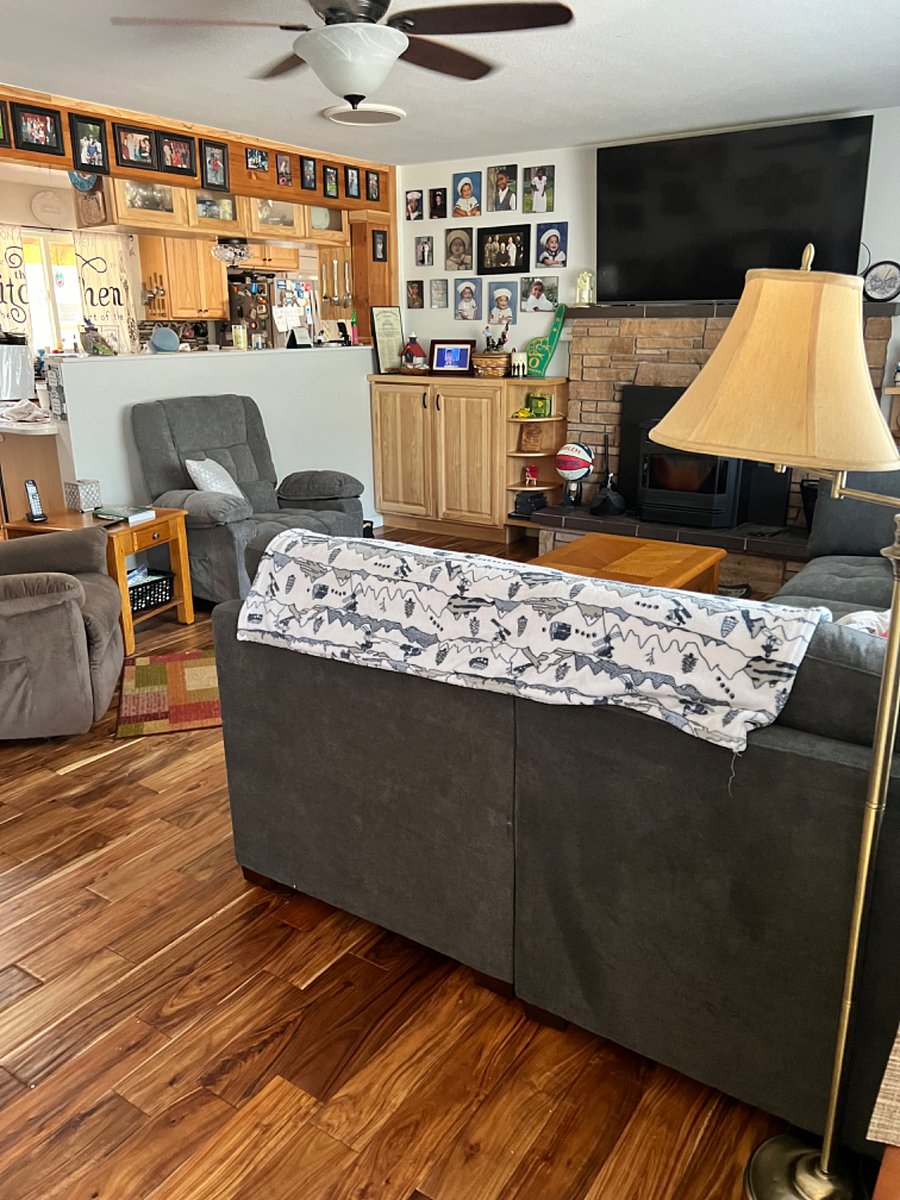 Shared living room space has a large comfortable couch, two recliners, and a pellet stove. 