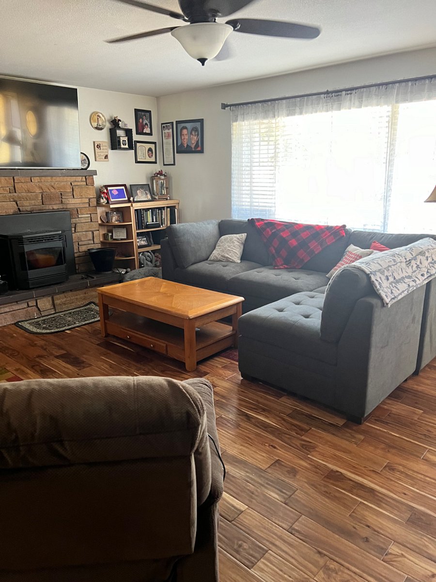 Shared living room space has a large comfortable couch, two recliners, and a pellet stove. 