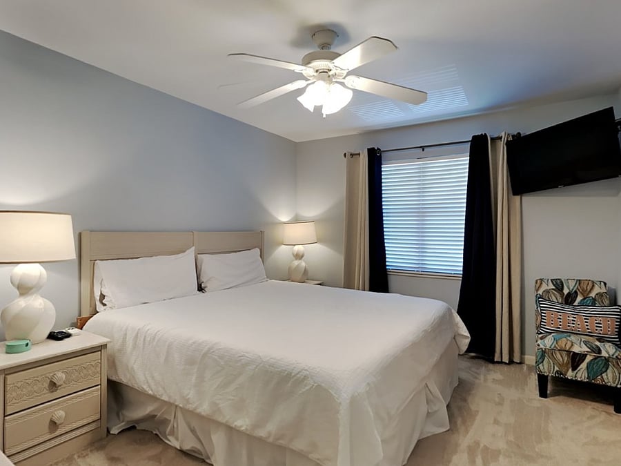 Second floor primary bedroom with carpet, dressers, night stands, blackout shades, HDTV, King bed, make-up / vanity area, walk-in closet and ensuite bathroom.