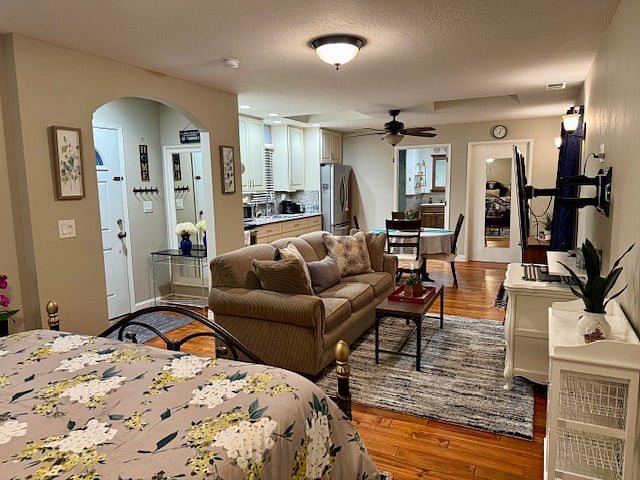 Facing living area from bed, also showing entryway (far left), bathroom entrance (far back left), workspace/closet entrance (far back right), both with full size mirror doors.