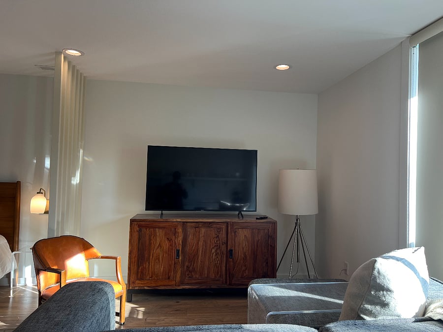 The living room comes with an apartment sized sectional, 85 in smart TV and acrylic coffee table that can be stored on or off the sofa footrest.