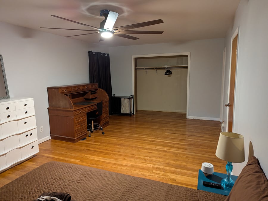 Master bedroom is approx 435 sqft with blackout curtains, roll top desk, dresser and mirror. Curtains closed.